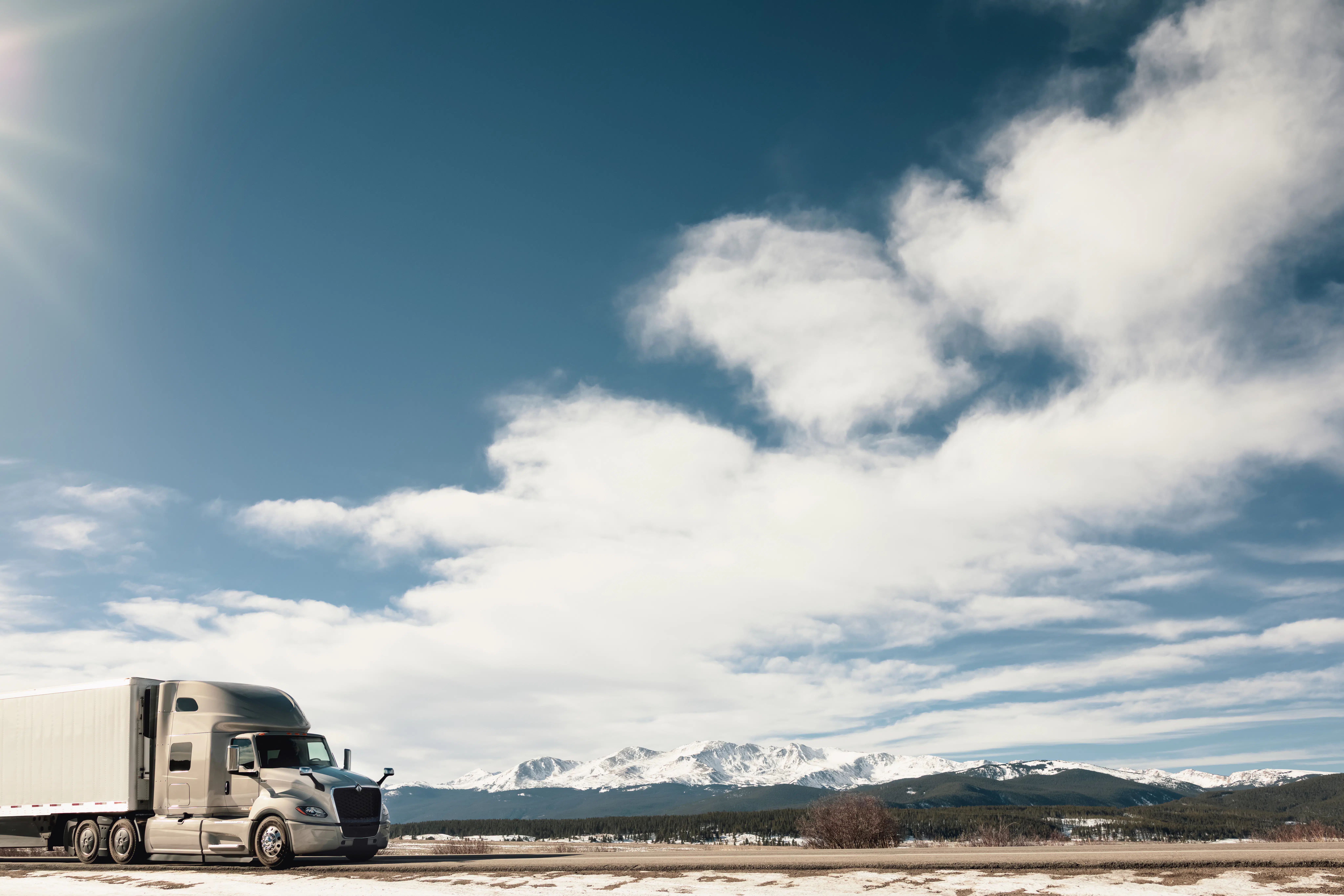 A grey truck driving along a vast landscape