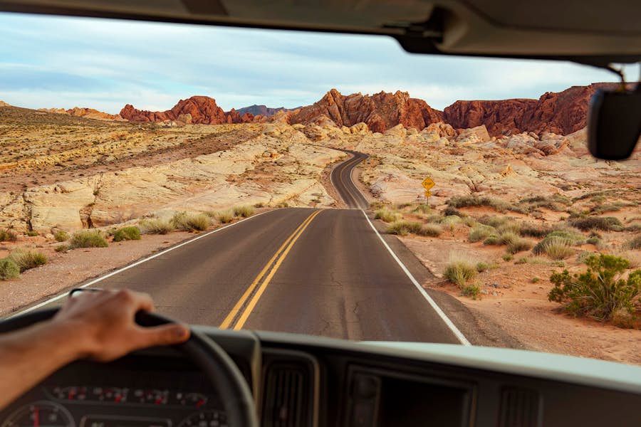 Driver Looking Through Windshield Driving On Desert Road