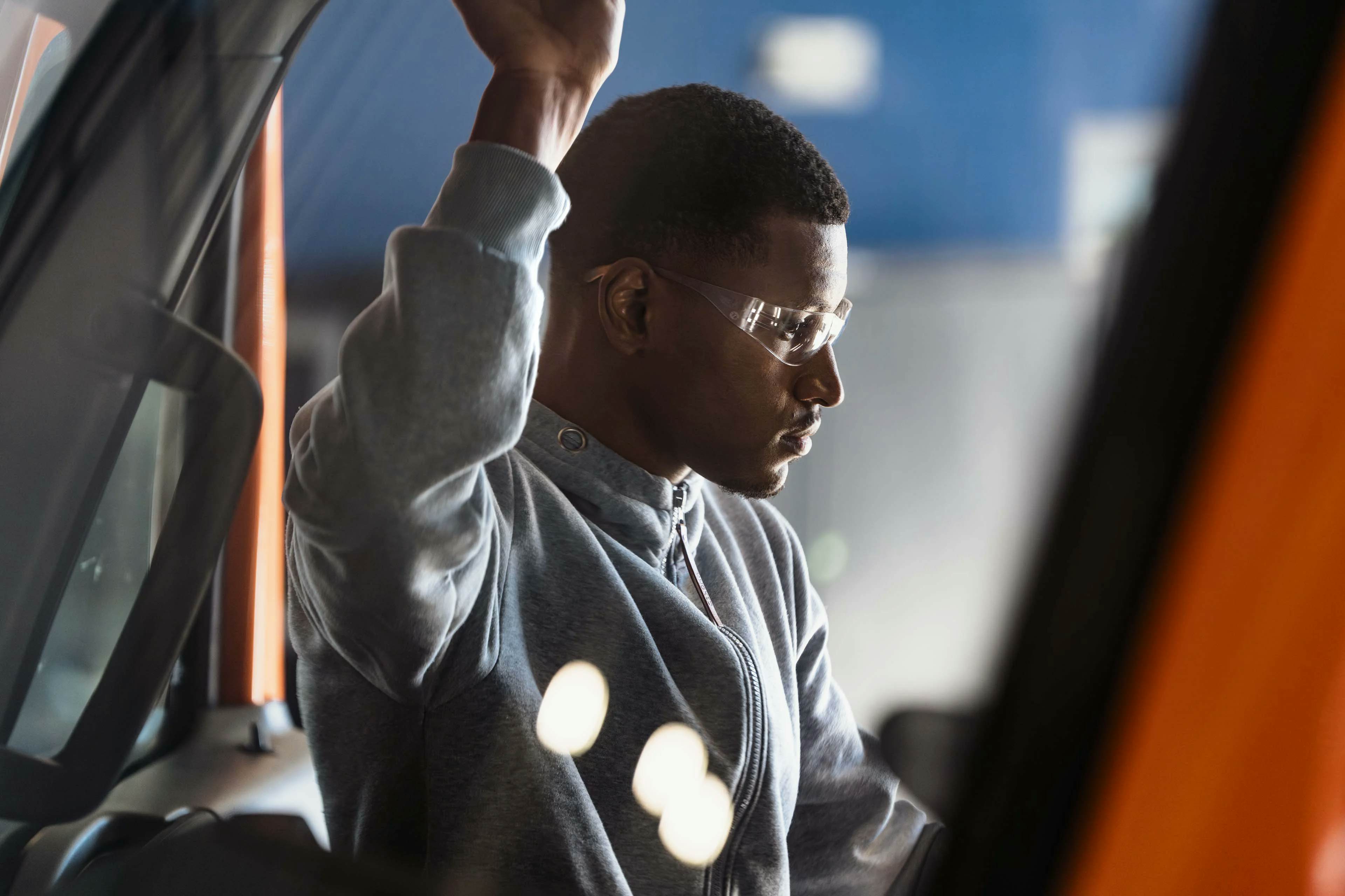 A person wearing safety goggles and holding his hand up