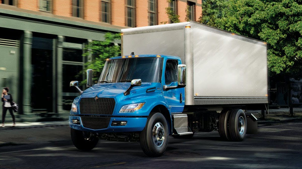 Blue eMV Series Truck on Road with People on Sidewalk