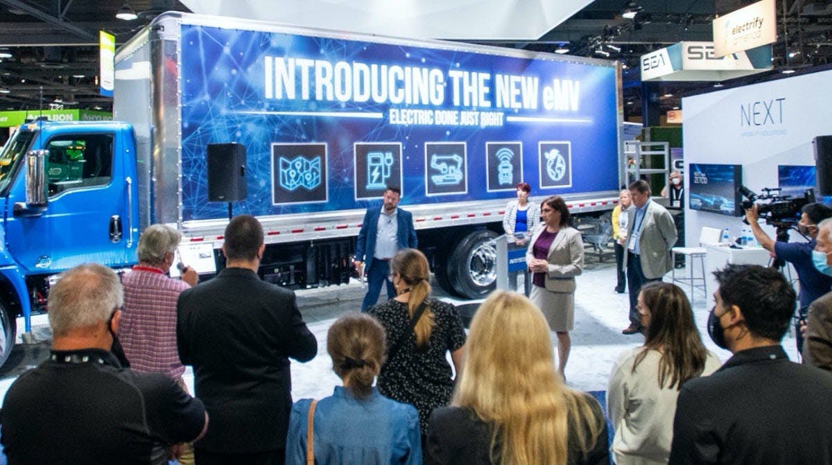 Blue Electric Truck in Showroom with People around It