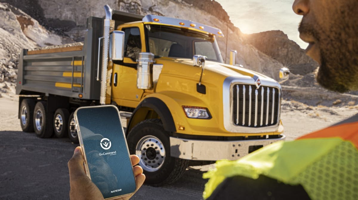 A person holding a phone in front of a yellow truck