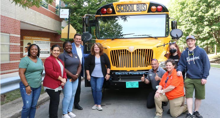 A group of people standing in front of a school bus