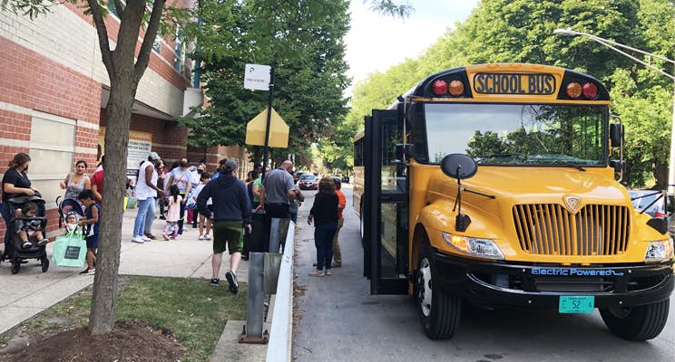 A group of people walking by a school bus