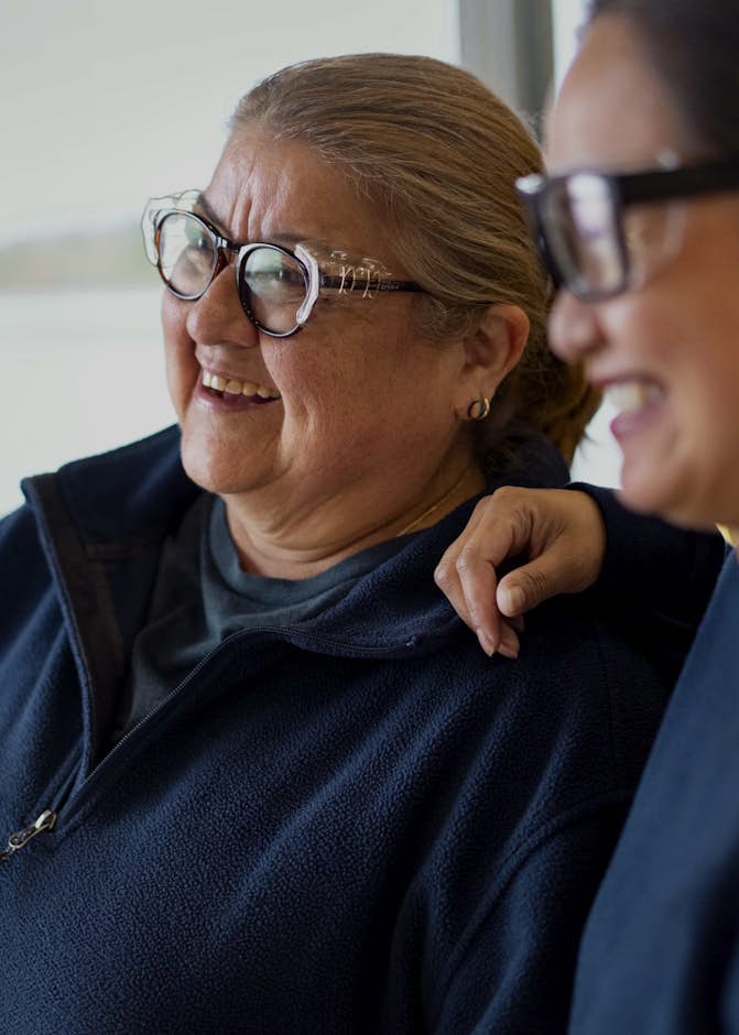 A person in glasses smiling next to another person