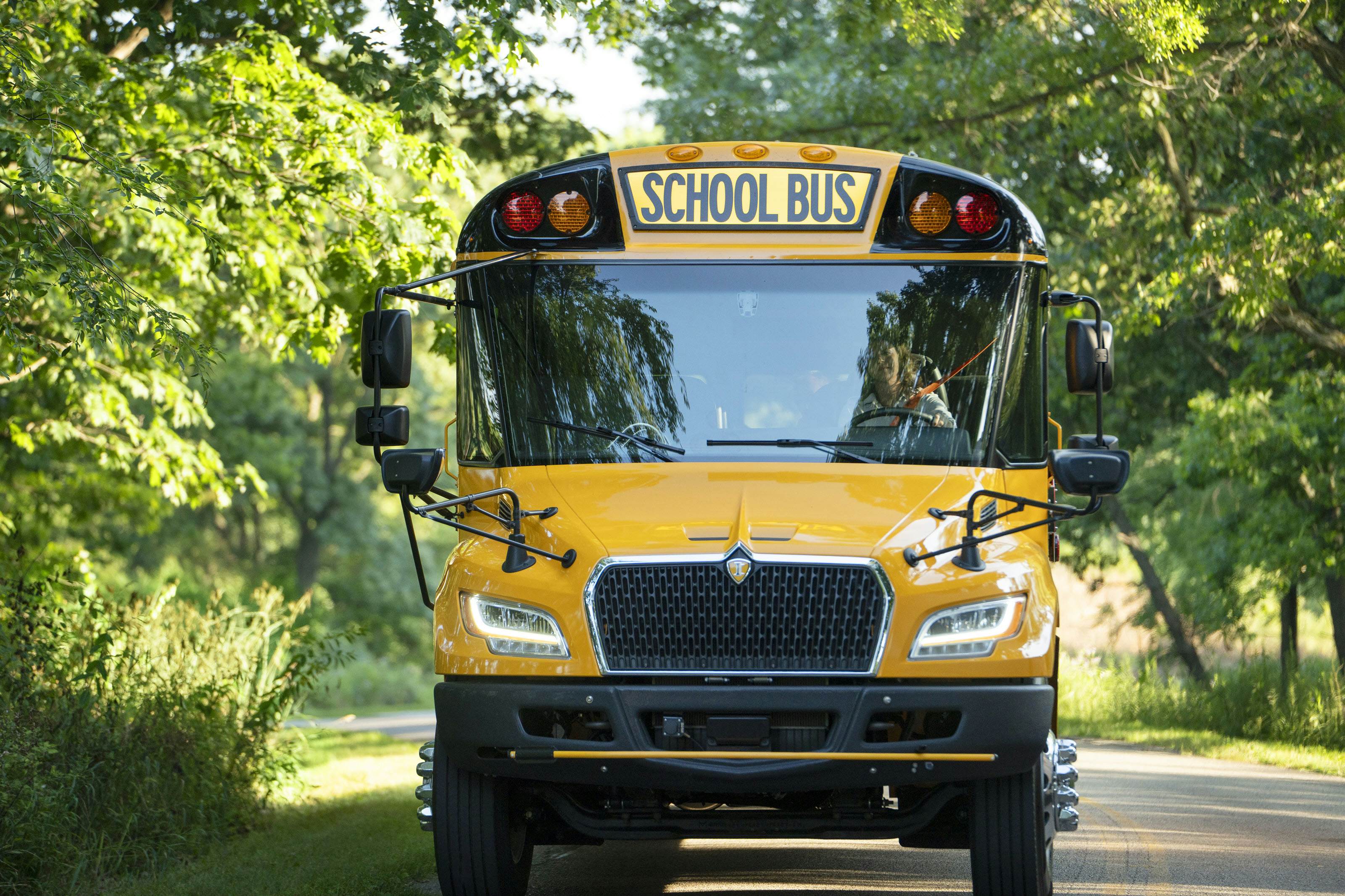 Bus driving down wooded road